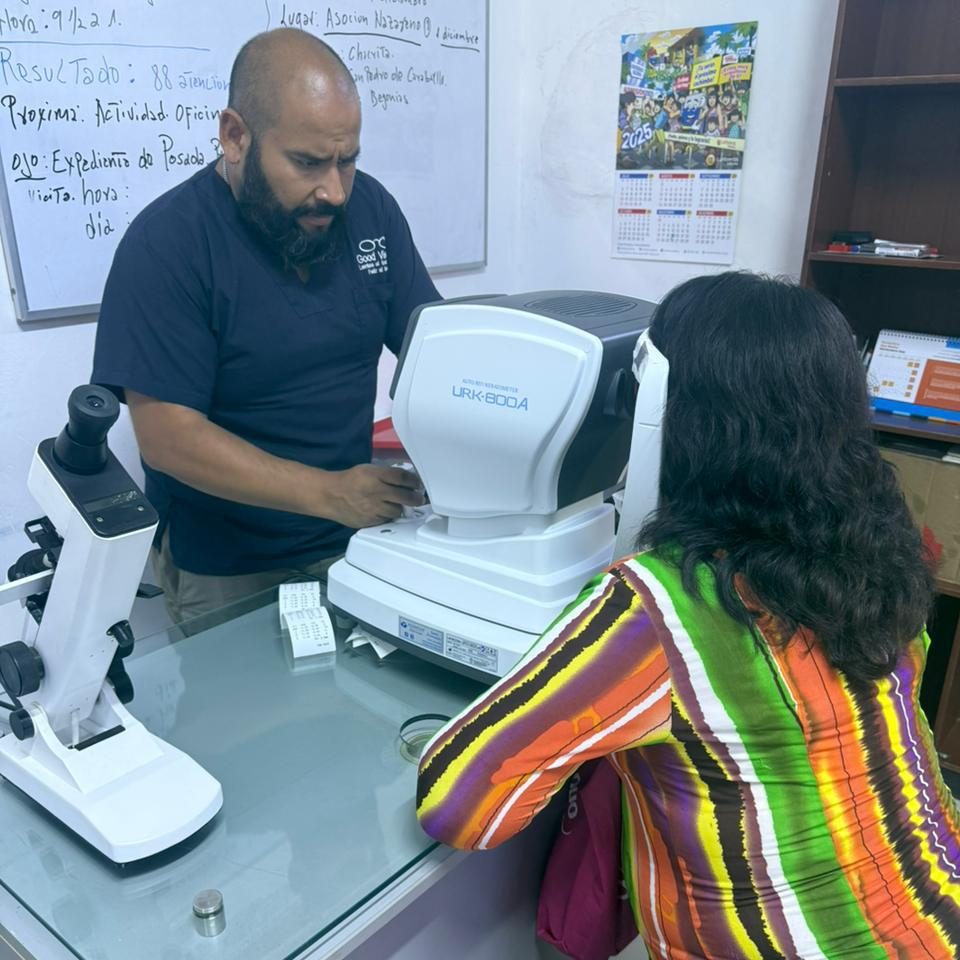 Fachkraft führt in einem Augencamp in Peru eine Refraktionsmessung mit einem Auto‑Refraktometer durch, während eine Patientin am Gerät sitzt.