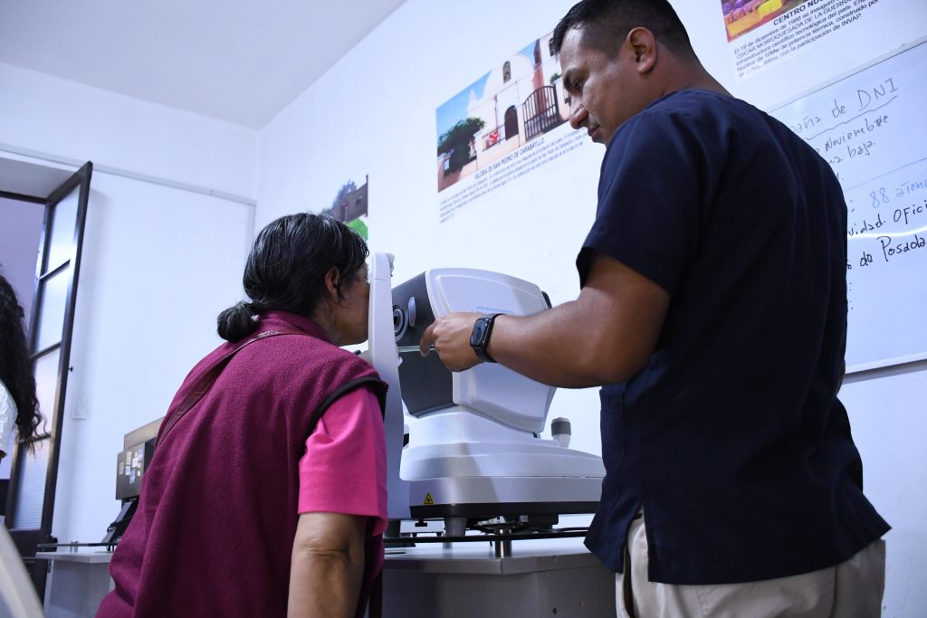 Frau erhält eine Augenuntersuchung mit einem Auto‑Refraktometer für Augencamps in Peru, durchgeführt von einer Fachkraft.