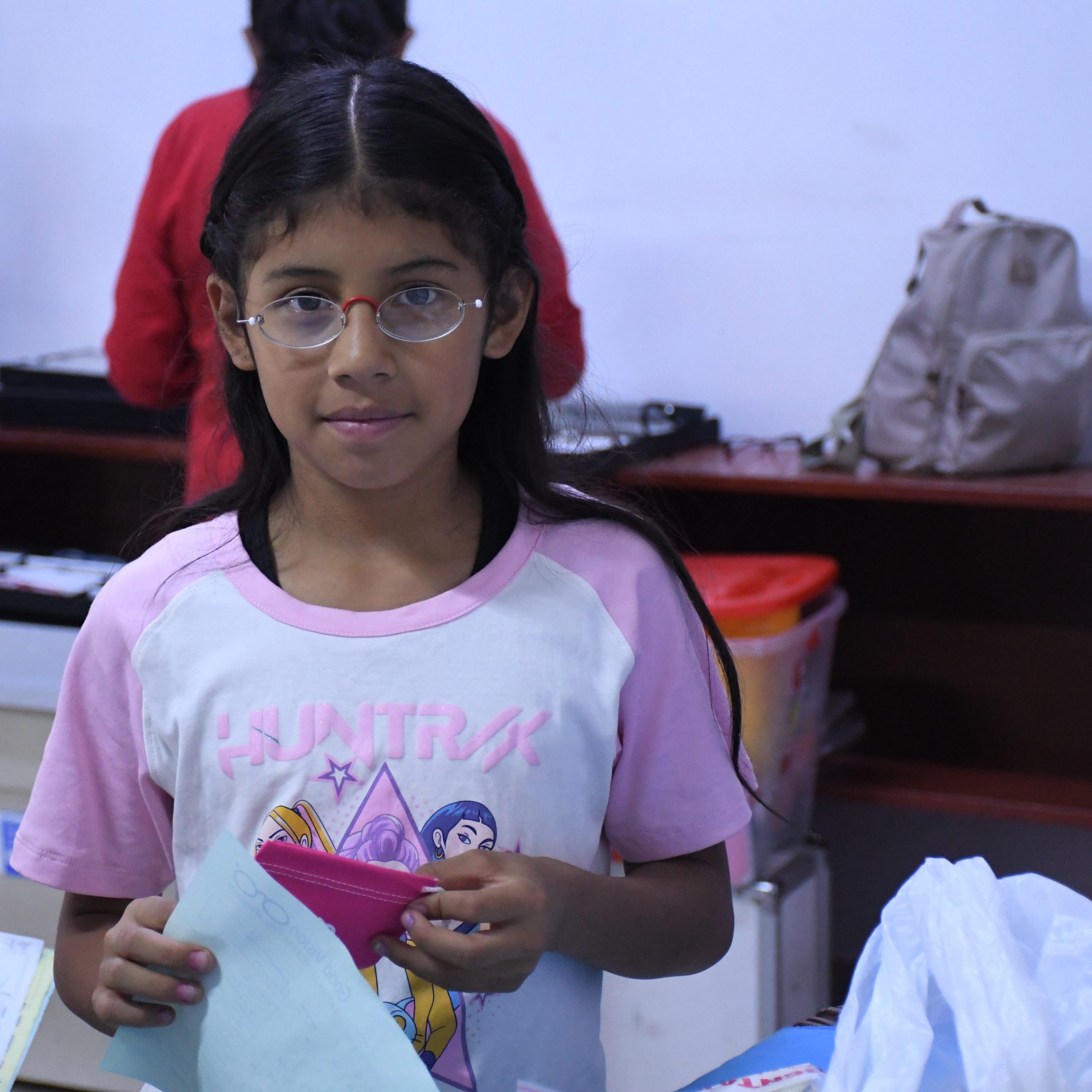 Mädchen in Peru trägt stolz ihre neue Brille und hält die Unterlagen aus dem Augencamp in der Hand